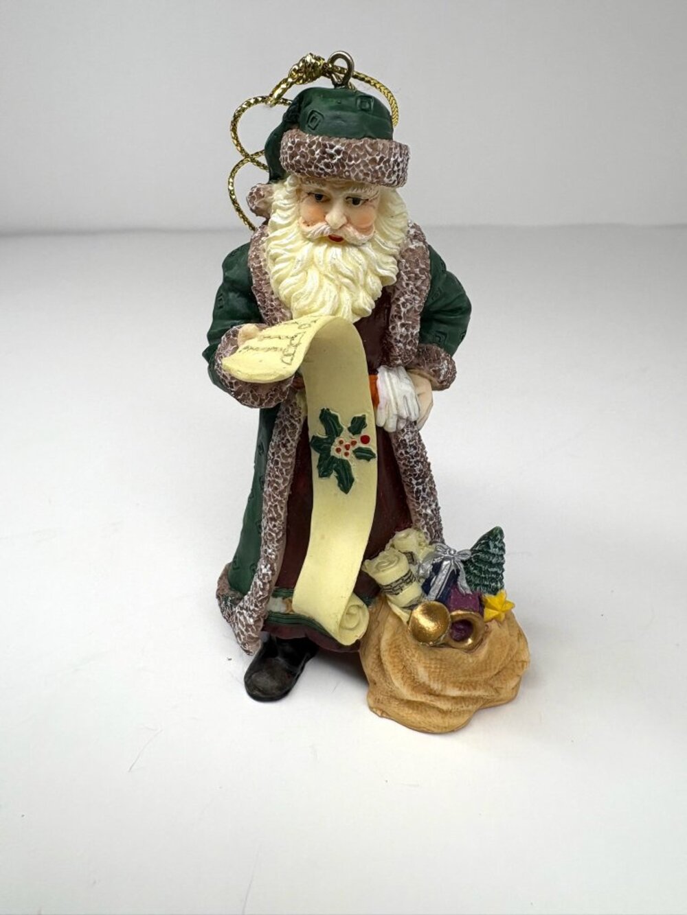 Father Christmas in a green fur-trimmed coat and hat, holding a long scroll list